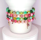 Handmade pastel tumbler bracelet set with pink, green, and gold beads, featuring small flamingo charms, stacked around a white tumbler.