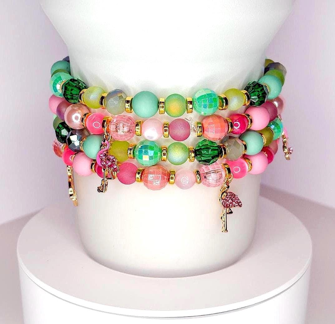 Handmade pastel tumbler bracelet set with pink, green, and gold beads, featuring small flamingo charms, stacked around a white tumbler.