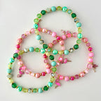 Tropical tumbler bracelet stack with pink and green beads, gold spacers, and flamingo charms, perfect for summer cup jewelry or tropical-themed drinkware decor.