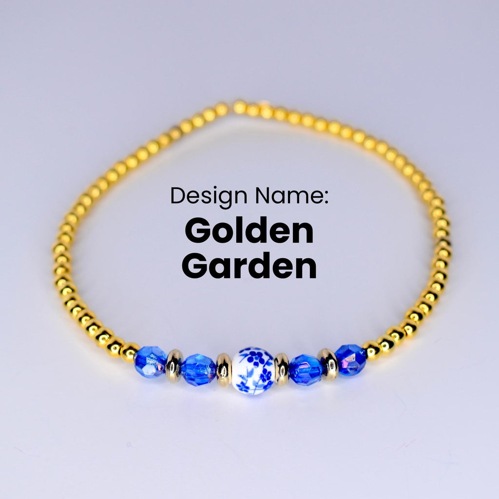 A gold beaded bracelet with a blue and white porcelain bead in the center. The bracelet is on a white background. Design Name: Golden Garden