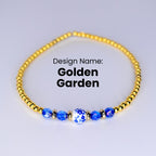 A gold beaded bracelet with a blue and white porcelain bead in the center. The bracelet is on a white background. Design Name: Golden Garden