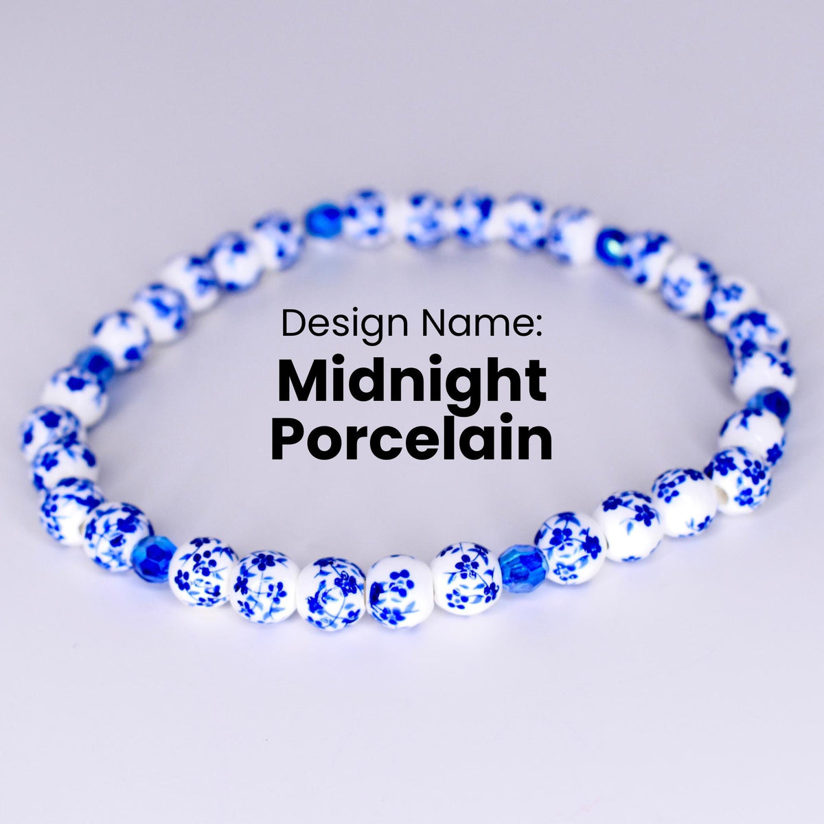 A white bracelet with blue floral designs on each bead. The bracelet has a few dark blue beads interspersed throughout. The text 'Design Name: Midnight Porcelain' is displayed below the bracelet.