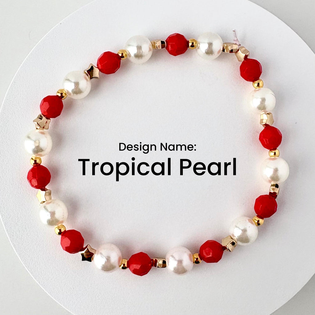 A beaded bracelet with the text "Tropical Pearl." The bracelet features alternating white pearl beads and red faceted beads, with gold-colored star and round accents.