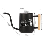 Black watering can with a wooden handle. The can has a spout and a white inscription that reads 'sometimes i wet my plants'. The can is 10.2 inches tall, 4.2 inches wide, and 5.4 inches deep.