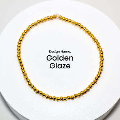A gold beaded bracelet with a simple design. The bracelet is on a white surface. Design Name: Golden Glaze