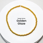 A gold beaded bracelet with a simple design. The bracelet is on a white surface. Design Name: Golden Glaze