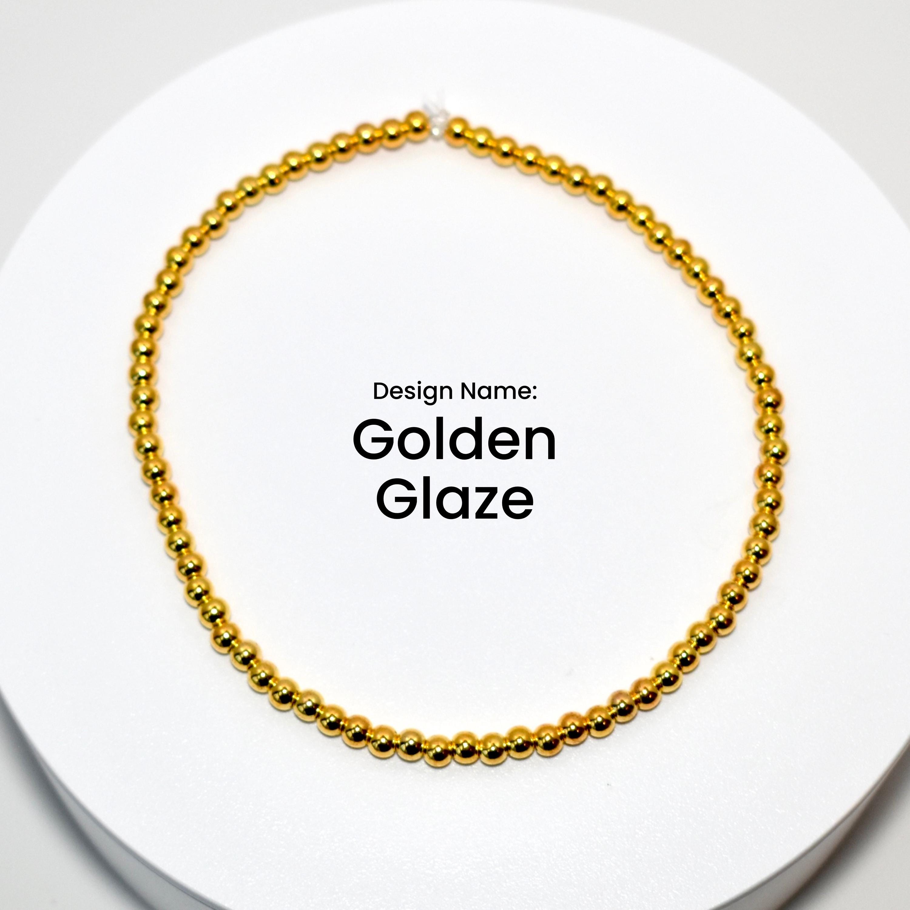 A gold beaded bracelet with a simple design. The bracelet is on a white surface. Design Name: Golden Glaze