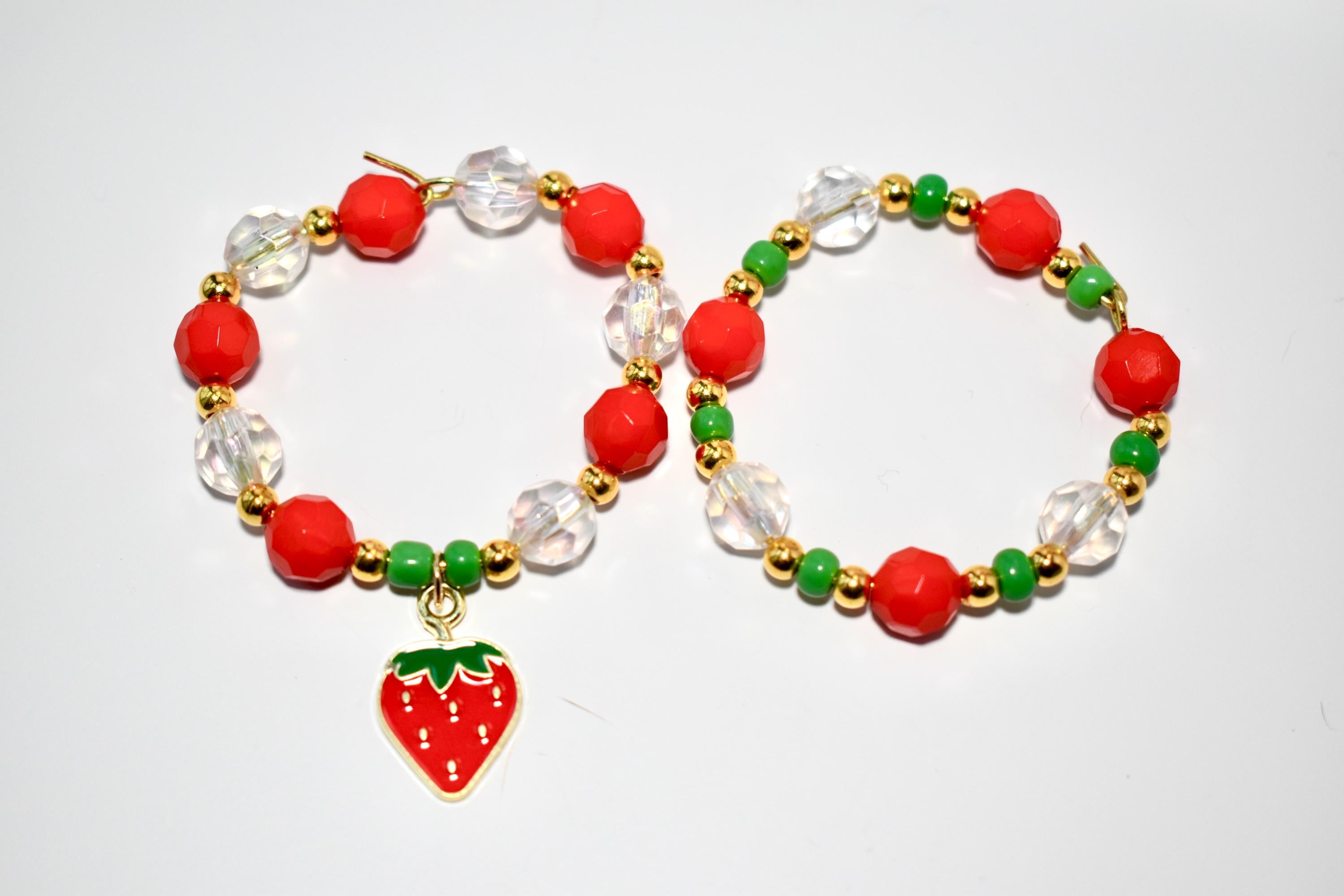 Two beaded tumbler handle bracelets with red, green, and clear beads. One bracelet has a strawberry charm.