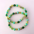 Two green and gold beaded bracelets with light blue, green, and gold beads. The bracelets are stacked on top of each other.