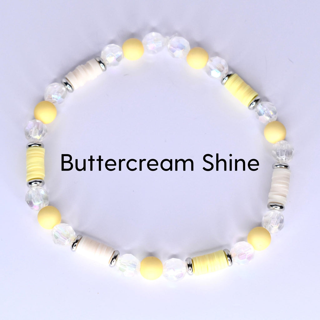 A beaded bracelet with the text "Buttercream Shine". The bracelet features a mix of yellow, white, and clear beads. The beads are arranged in a circular pattern, creating a stylish accessory.