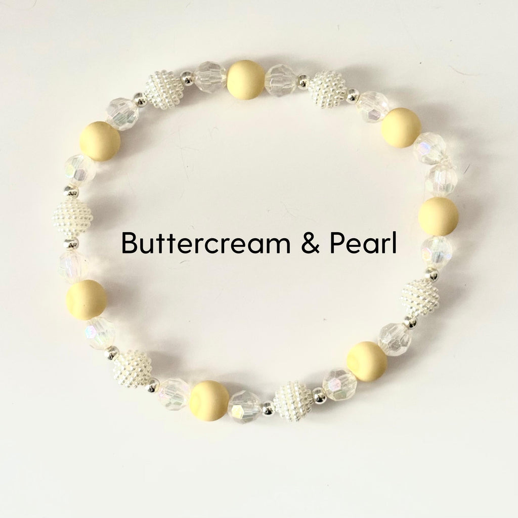 A beaded bracelet featuring a mix of creamy yellow and pearl-like beads. The bracelet includes round, matte yellow beads, textured white beads, and clear, faceted beads. The text "Buttercream & Pearl" is displayed.