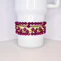 A set of five bracelets featuring a mix of deep purple and gold beads. The bracelets are stacked on top of each other, creating a layered look.