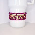 A set of five bracelets featuring a mix of deep purple and gold beads. The bracelets are stacked on top of each other, creating a layered look.
