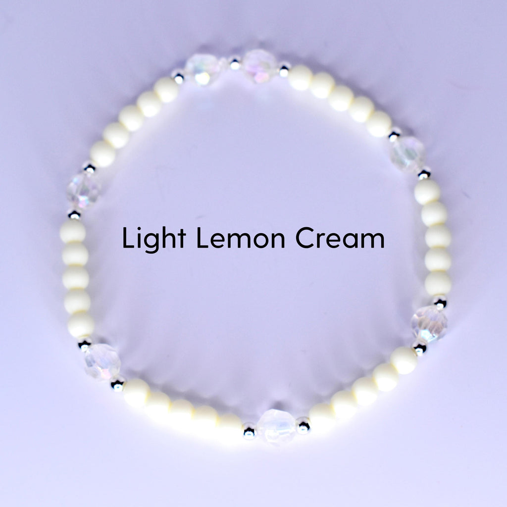 A bracelet with light lemon cream-colored beads and iridescent crystal accents. The bracelet has small silver-colored spacers between the crystal and cream-colored beads. The text "Light Lemon Cream" is displayed.