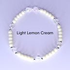 A bracelet with light lemon cream-colored beads and iridescent crystal accents. The bracelet has small silver-colored spacers between the crystal and cream-colored beads. The text "Light Lemon Cream" is displayed.