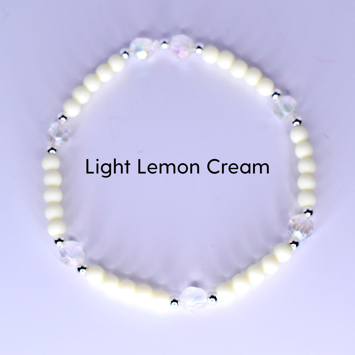 A bracelet with light lemon cream-colored beads and iridescent crystal accents. The bracelet has small silver-colored spacers between the crystal and cream-colored beads. The text "Light Lemon Cream" is displayed.
