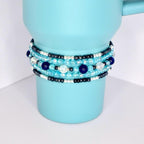 Handcrafted stack of tumbler bracelets with deep blue, turquoise, silver, and translucent beads, displayed on a two-tone tumbler.