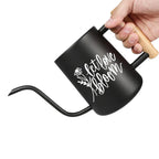 Black gooseneck watering can with a wooden handle. The watering can features a long, curved spout for precise watering. White script on the side reads 'let love bloom' with a floral design. The handle is made of light-colored wood, providing a comfortable grip for gardening.