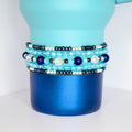 Handmade blue Stanley bracelets with faceted beads in aqua and sapphire, accented with silver and black, displayed on a dual-tone blue drink tumbler. The bracelets are pictured on the blue Agave Stanley 40oz cup.