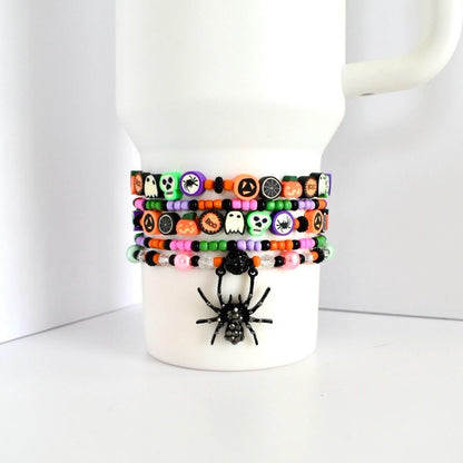 Set of 5 beaded Halloween bracelets for tumbler cups with festive themed charms—skulls, jack-o’-lanterns, spiderwebs, ghosts, and rhinestone spider charm.