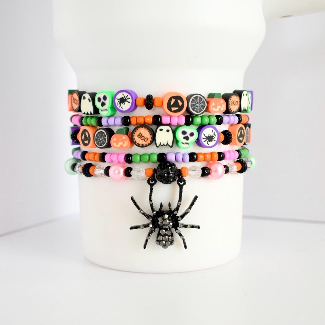 Vibrant stack of 5 Halloween tumbler bracelets with spooky polymer beads and a dangling rhinestone spider charm, designed in festive fall colors