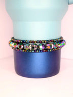 Stack of 3 iridescent tumbler bracelets with multicolor faceted beads and metallic seed beads, shown on a blue gradient tumbler for a bold, reflective style.
