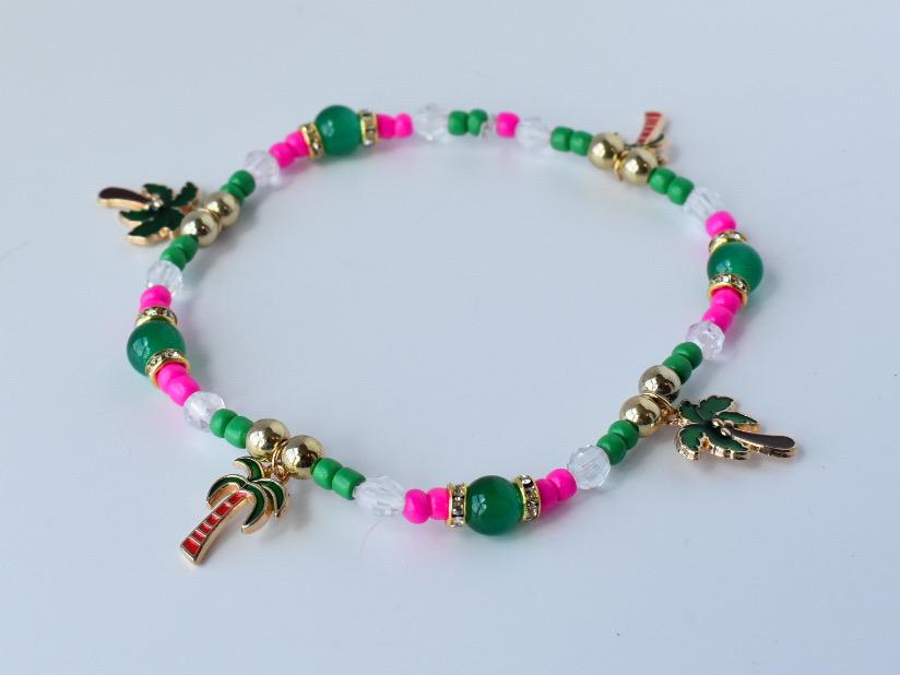 Colorful palm tree charm bracelet made of green, pink, and translucent beads with gold accents; shown as a closed loop for a beachy boho jewelry style.