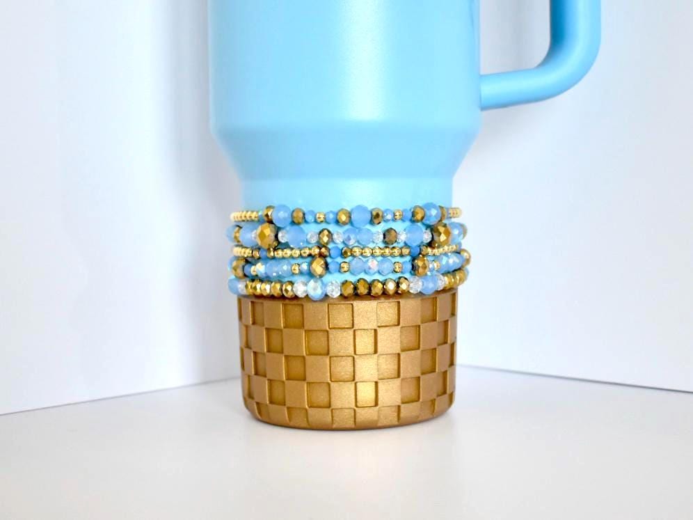 Messi Stanley bracelet stack featuring faceted blue beads, gold accents, and crystal detailing, wrapped around a blue and gold Stanley.