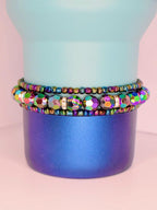 Set of 3 rainbow-toned tumbler bracelets featuring faceted glass beads and reflective metallic details, styled on a modern blue ombre tumbler.