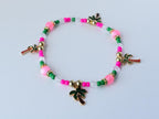 Single tropical bracelet with alternating green, pink, and clear beads, gold spacers, and multiple palm tree charms, arranged in a circle on a white surface.