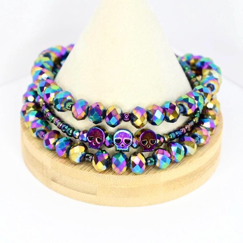 Stacked holographic beaded tumbler bracelets with metallic skull accents