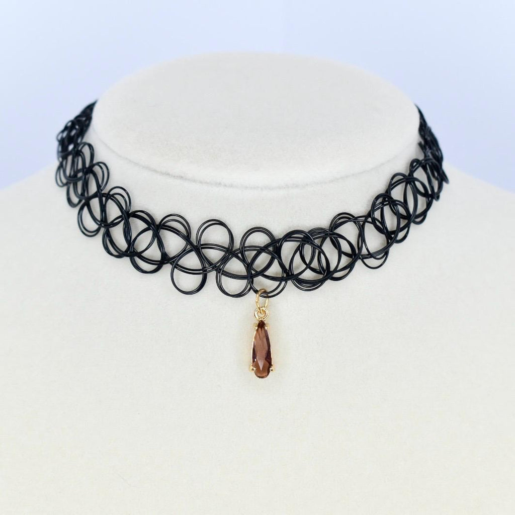 Black choker necklace with a pendant. The necklace is made of a series of interconnected loops. A teardrop-shaped pendant hangs from the center of the necklace. The pendant is a brown color and has a gold-colored bail.