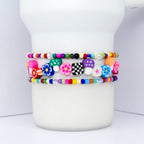 Three colorful beaded bracelets with flower, mushroom, and checkerboard charms. The bracelets feature a variety of bright colors, including pink, blue, green, and orange. The bracelets are stacked on top of each other.
