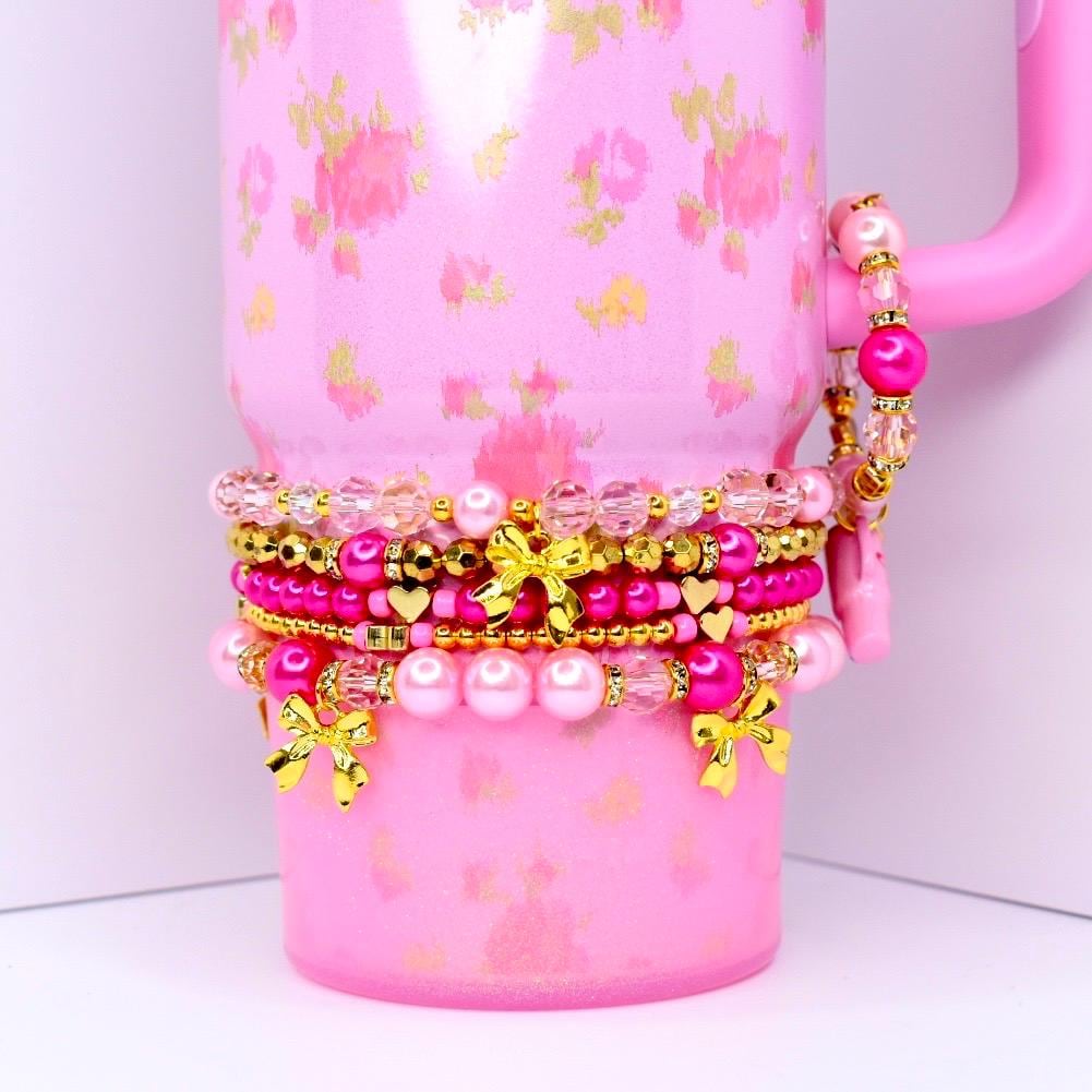 Stacked pink beaded tumbler bracelets with gold bow charms pearls and crystal beads girly drinkware accessory.