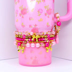 Stacked pink beaded tumbler bracelets with gold bow charms pearls and crystal beads girly drinkware accessory.