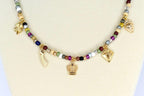 A beaded necklace with a variety of colorful beads and gold-colored charms. The charms include a crown, a diamond, a shooting star, a strawberry, and a four-leaf clover. The necklace is displayed on a white surface.