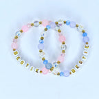 Two beaded bracelets with the word 'BESTIE' spelled out in white letter beads. The bracelets feature a mix of pink, blue, and clear beads with gold accents. The beads are arranged in a pattern, creating a colorful and stylish accessory. The bracelets are likely for friendship or as a gift.