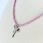 Pink seed bead necklace featuring a dainty silver bow pendant – trendy handmade jewelry gift for her.