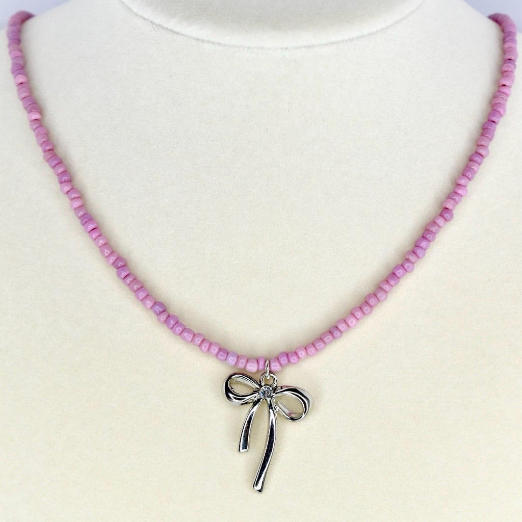 Handmade pink beaded necklace with silver bow charm – cute pastel jewelry for everyday wear.
