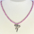 Handmade pink beaded necklace with silver bow charm – cute pastel jewelry for everyday wear.