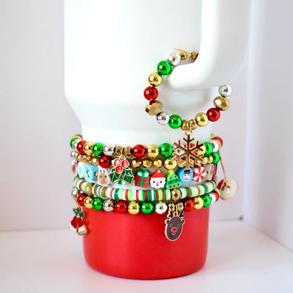 Christmas tumbler bracelet stack with 5 beaded red, green, and gold holiday bands featuring Santa, reindeer, and snowflake charms on a stainless steel tumbler.