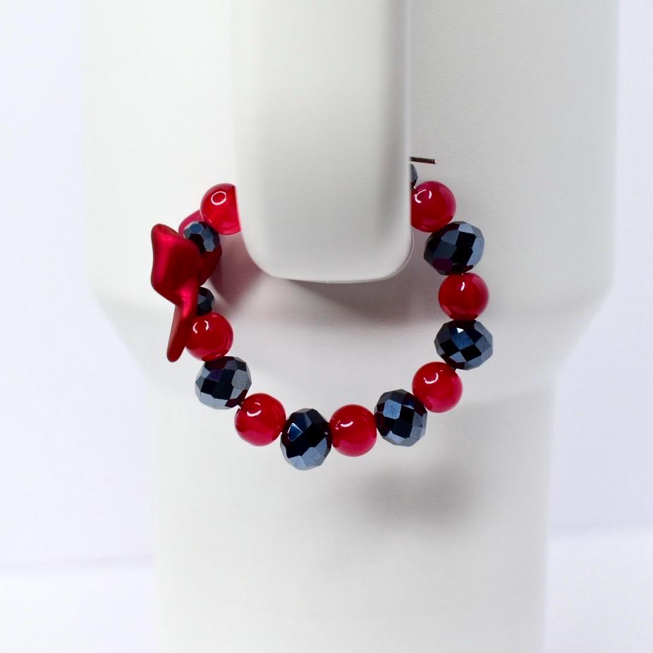 A red and black beaded bracelet with a bow charm. The bracelet features faceted black beads and round red beads. The bow charm is a deep red color. The bracelet is displayed on a white background.