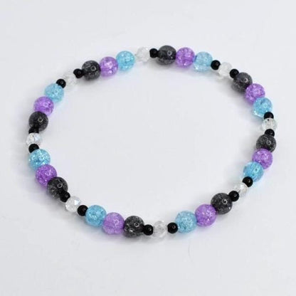 A beaded bracelet featuring a variety of colorful beads. The bracelet includes light blue, purple, black, and clear beads. The beads are strung together to form a circular shape. The bracelet is on a white background.
