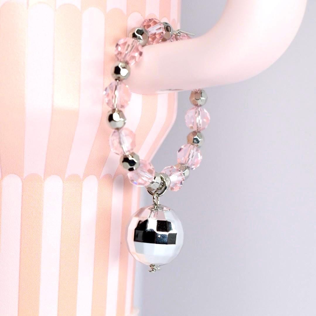 A pink beaded tumbler handle charm with silver accents and a small disco ball charm. The bracelet is made of clear pink beads and silver beads. The disco ball charm is silver and reflective.