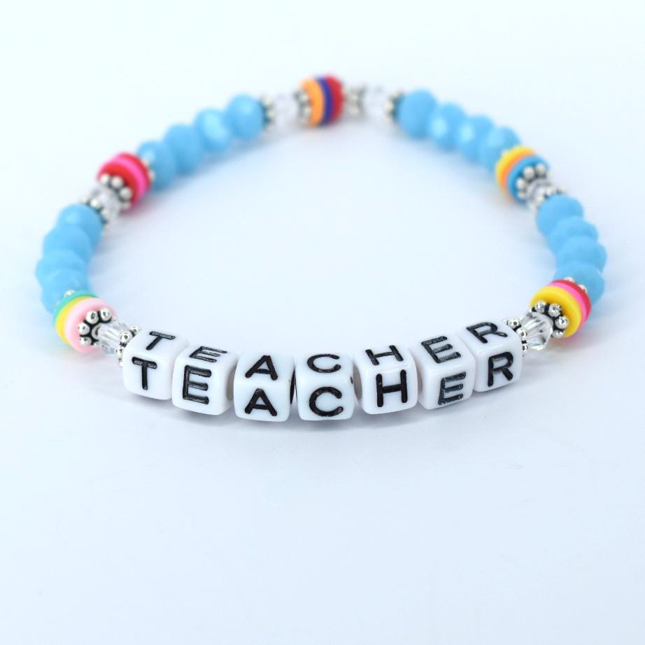 A beaded bracelet with the word "TEACHER" spelled out in white letter beads. The bracelet features light blue beads, silver accents, and colorful accent beads in pink, yellow, orange, and blue. A perfect gift for a teacher.