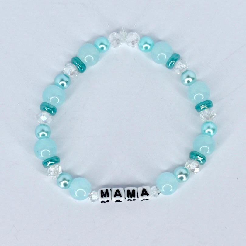 A beaded bracelet featuring light blue and clear beads. The bracelet includes the word "MAMA" spelled out in white letter beads. The beads are strung together with a clear elastic cord.