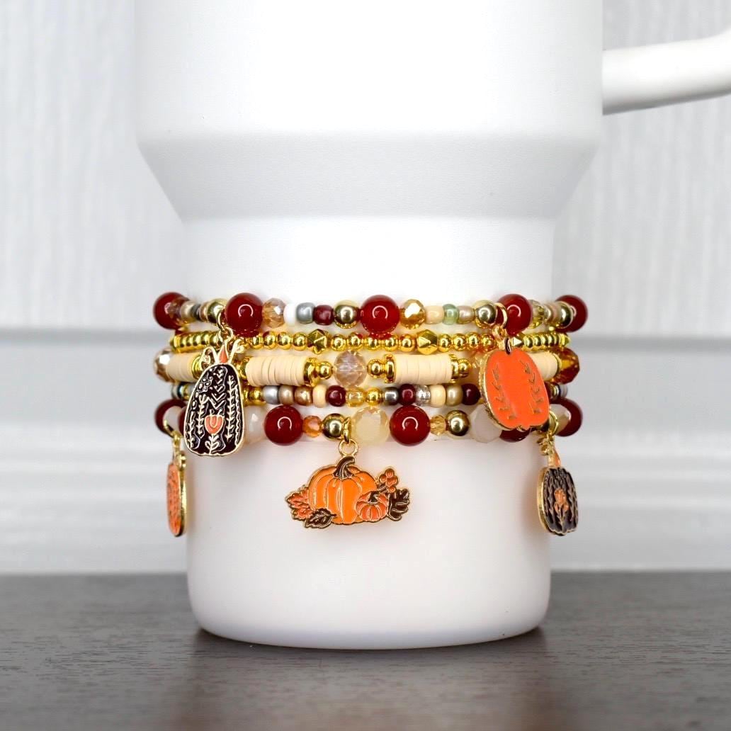 Thanksgiving tumbler bracelet stack with pumpkins, autumn charms, and gold beads. Festive fall beaded wrap for seasonal drinkware.