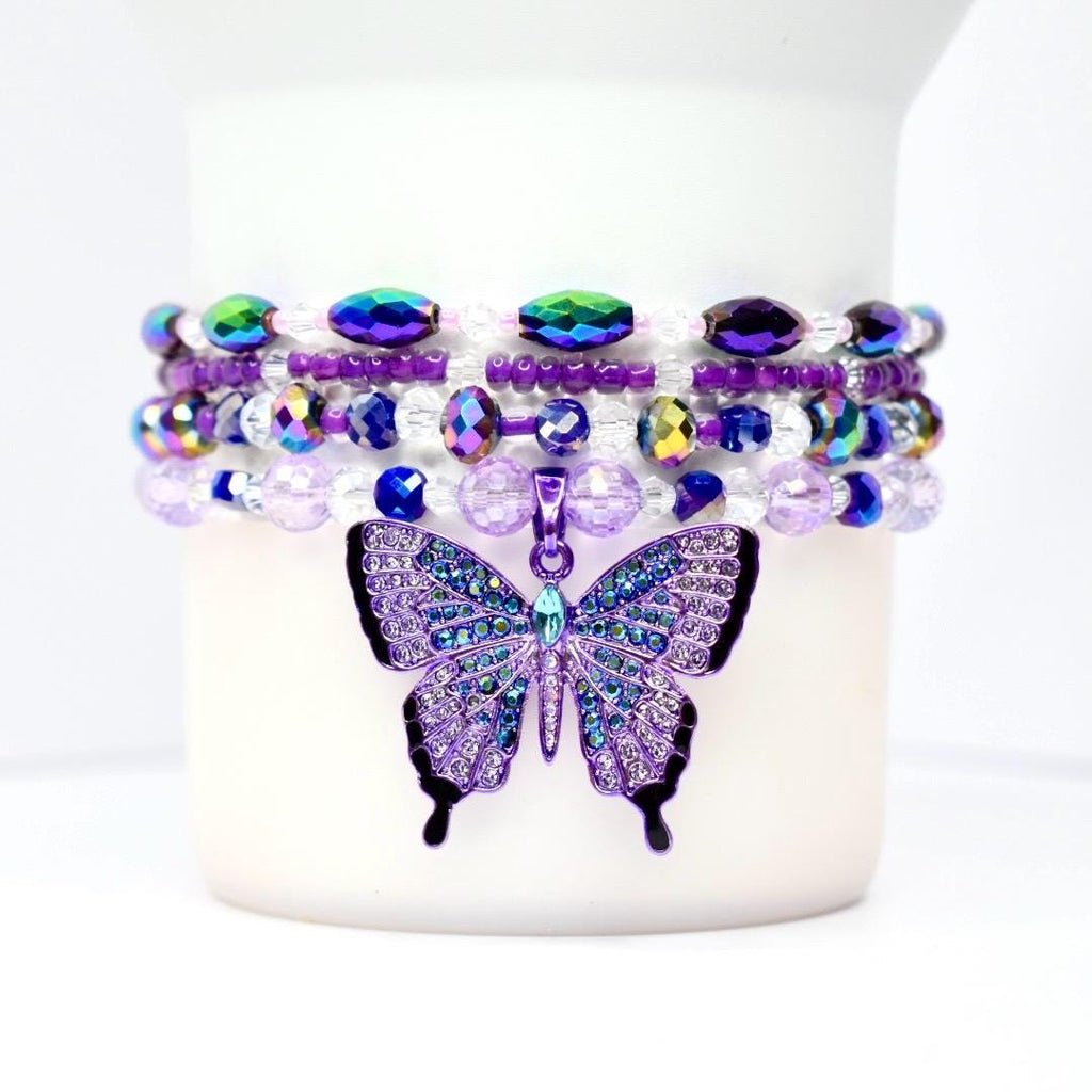 Close-up of bead details: matte purple, translucent and faceted glass, metallic spacer beads, and the butterfly charm catching light.