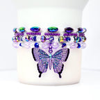 Close-up of bead details: matte purple, translucent and faceted glass, metallic spacer beads, and the butterfly charm catching light.
