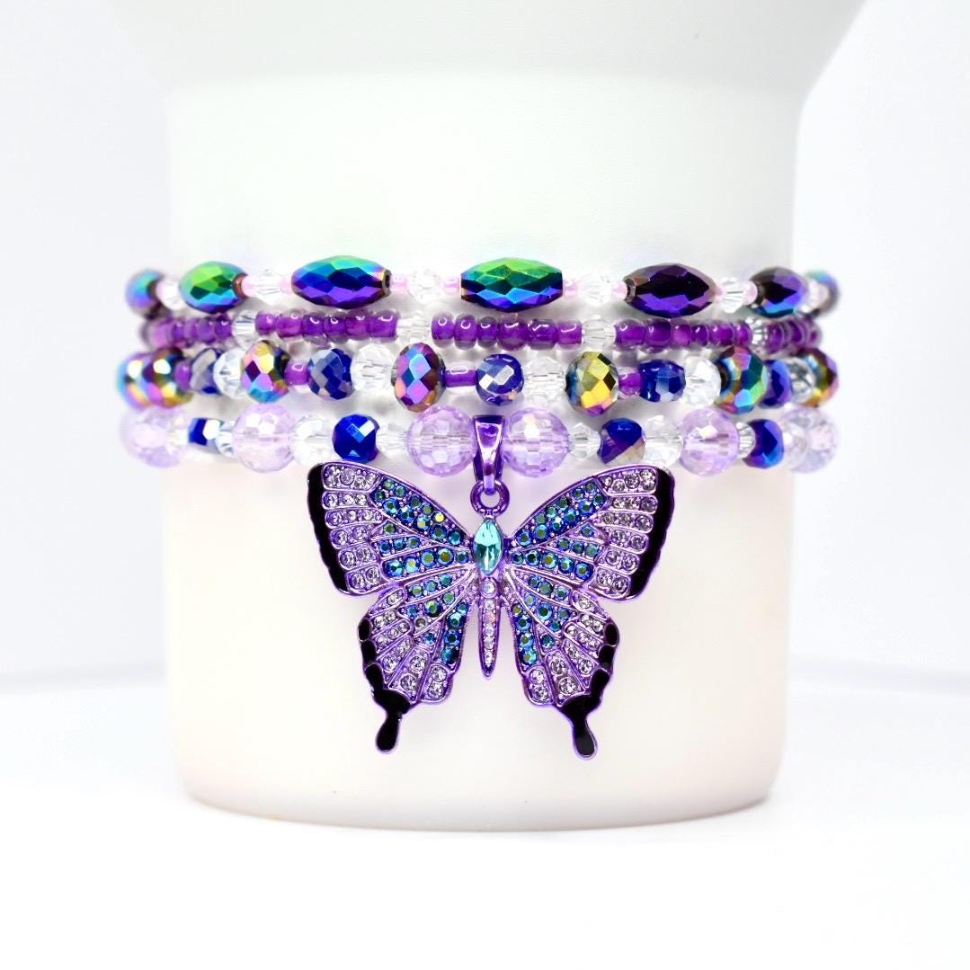 Close-up of bead details: matte purple, translucent and faceted glass, metallic spacer beads, and the butterfly charm catching light.